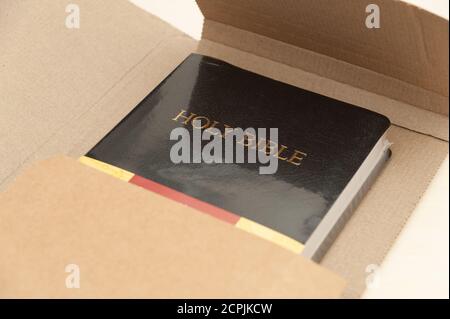 Versandkarton mit der Heiligen Bibel, die geöffnet wird. Draufsicht. Nahaufnahme. Stockfoto