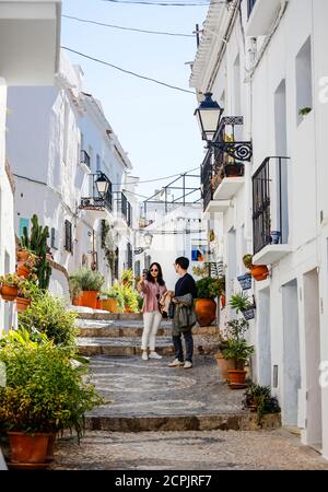 Asiatische Touristen fotografieren in malerischen Straßen im weißen Bergdorf Frigiliana, Frigiliana, Provinz Malaga, Andalusien, Spanien Stockfoto