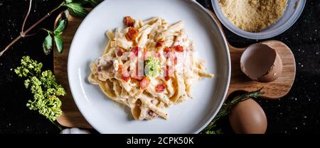 Pasta Carbonara in weißer Schale, mit frischen Zutaten Stockfoto