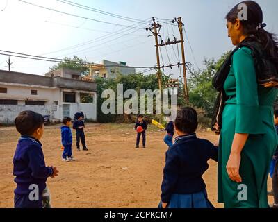 DISTRIKT KATNI, INDIEN - 17. JANUAR 2020: Indische Vorschulkinder spielen zusammen mit der Lehrerin auf dem Bodenfeld auf dem Sportplatz. Stockfoto