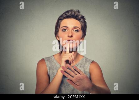 Nahaufnahme Porträt ernsthafte aufgeregt Frau Finger, Hand auf Lippen, shhh Geste fragen, ruhig sein Stille isoliert auf grauen Wand Hintergrund. Negative Gesichtsbehandlung Stockfoto