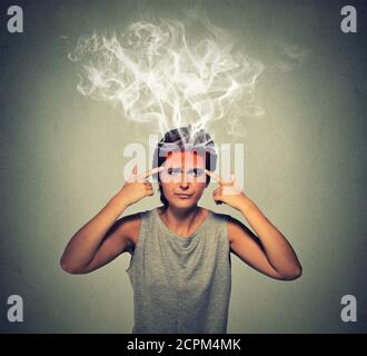 Portrait junge gestresste Frau denken zu hart Dampf kommen aus dem Kopf isoliert auf grauen Wand Hintergrund. Gesichtsausdruck Emotion Wahrnehmung. Brennen Stockfoto