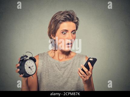 Junge Frau mit Handy und Wecker gestresst laufen Spät Stockfoto