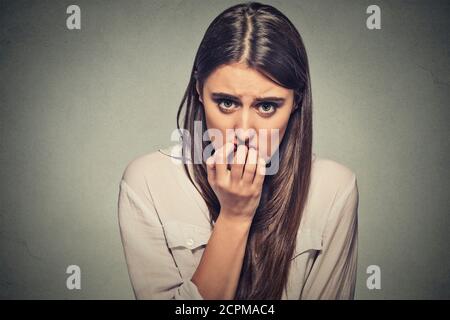 Closeup Portrait junge unsicher zögerlich nervös Frau beißen ihre Fingernägel verlangen nach etwas oder ängstlich, isoliert auf graue Wand Hintergrund. Negati Stockfoto