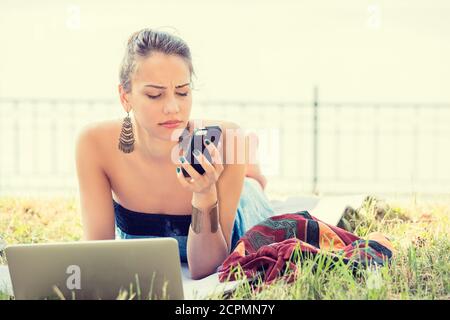 Verärgert traurig skeptisch unglücklich ernste Frau SMS auf Telefon im Freien im Park unzufrieden mit dem Gespräch. Negative menschliche Emotion Gesichtsausdruck feeli Stockfoto