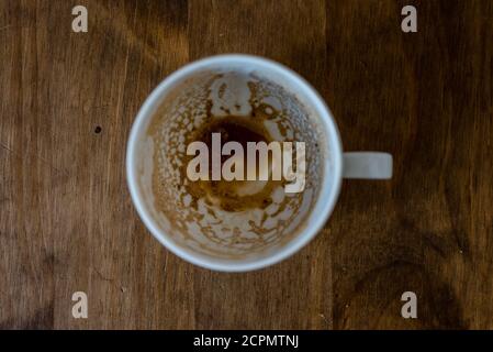 Gebrauchte weiße Kaffeetasse von oben fotografiert auf einem Holztisch Stockfoto