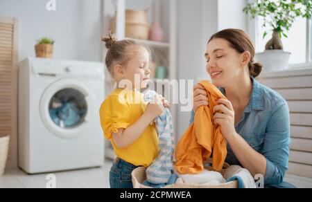 Schöne junge Frau und Kind Mädchen kleinen Helfer haben Spaß und Lächeln, während die Wäsche zu Hause. Stockfoto