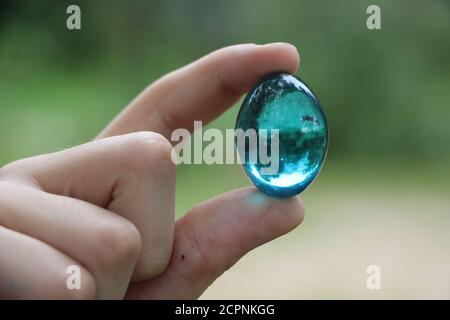 Kristall Glaskugel in der menschlichen Hand auf unschärfem Gras Hintergrund. Umwelt schonen, sauberen grünen Planeten retten, Ökologie-Konzept Stockfoto