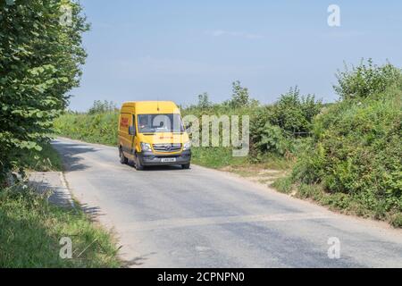 Gelber DHL-Lieferwagen (Mercedes Sprinter) auf einer ländlichen Straße in Cornisch. Für ländliche Lieferdienste in Großbritannien, Paketlieferungen, Kurierdienste. Stockfoto