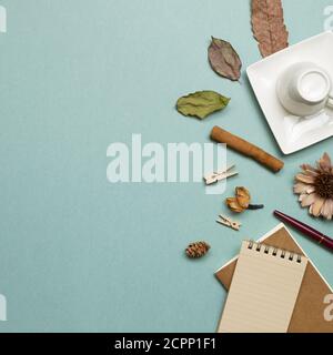 Herbstkonzept. Notizbuch und Tasse mit trockenen Blättern auf grünem Hintergrund. Flach liegend, Draufsicht, Kopierraum. Arbeits- und Studienort Stockfoto