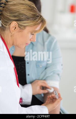 Arzt, der Wattestäbchen auf den injizierten Bereich legt Stockfoto