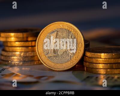 Nahaufnahme einer Euro-Münze mit Euro-Münzstapeln auf einem Hundertstel Euro-Schein. Stockfoto