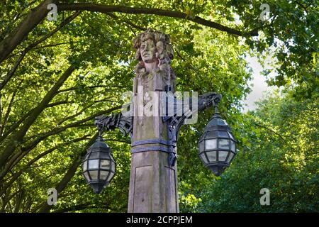 Alte Steinlaterne an der Einkaufsmeile Königsallee in der Düsseldorfer Innenstadt, umgeben von alten grünen Bäumen. Stockfoto