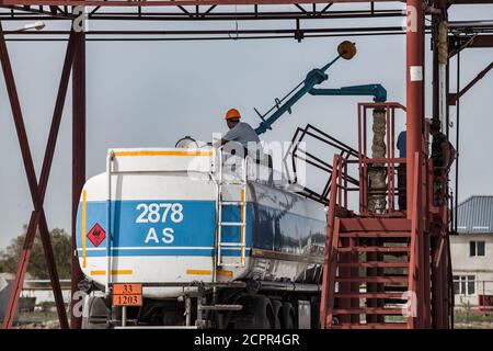 Tankwagen-Tankstelle oder -Terminal in der Ölraffinerie. Arbeiter auf dem Tank. Blauer Himmel. Stockfoto