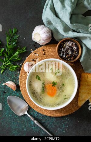 Hühnersuppe mit Gemüse auf einer Tischplatte aus dunklem Stein. Draufsicht flach lagen Hintergrund. Stockfoto
