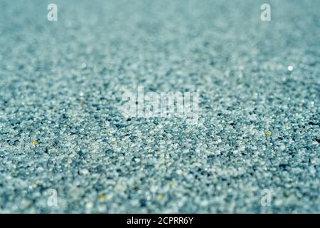 Winzige Kiesstruktur auf blauer, heller Betonwand. Textur Hintergrund nahtlose Kiesboden. Selektiver Fokus. Nahaufnahme des Makros Stockfoto
