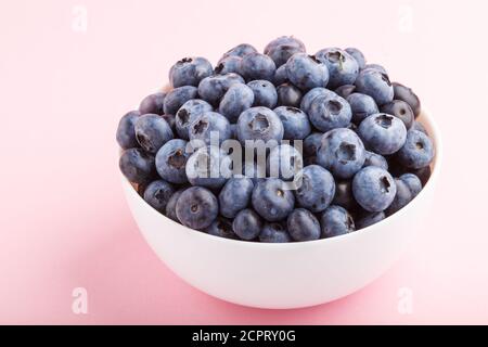 Frische Heidelbeere in weißer Schale auf rosa Hintergrund. Seitenansicht, Nahaufnahme. Stockfoto