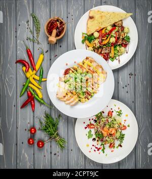 Essen. Set von Gerichten Salate auf dem Tisch. Auf einem hölzernen Hintergrund. Stockfoto