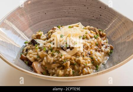 Risotto mit Pilzen und Käse in handwerklichem Steingut serviert. Stockfoto