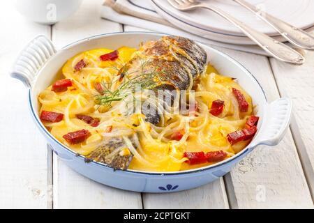 Köstliche Ofenforelle mit Kartoffeln, Zwiebeln und Schinken. Stockfoto