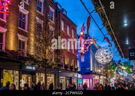 Menschenmassen, die entlang der Carnaby Street London mit den Ocean themed Christmas Lights Overhead, London, UK, laufen Stockfoto