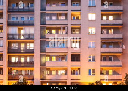 Balkone und Fenster auf verschiedenen Etagen des Wohnblocks in Der Abend Stockfoto