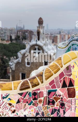 Barcelona, Park Güell, Bank mit zerbrochener Keramik dekoriert, Porter's Lodge im Hintergrund Stockfoto