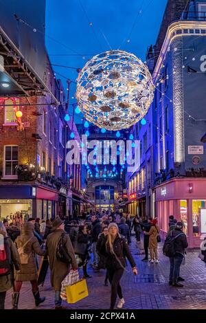 Menschenmassen, die entlang der Carnaby Street London mit den Ocean themed Christmas Lights Overhead, London, UK, laufen Stockfoto