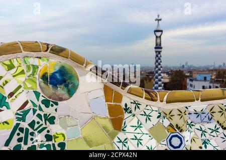 Barcelona, Park Güell, Bank mit zerbrochenen Keramiken, im Hintergrund Turm der Portier-Lodge dekoriert Stockfoto