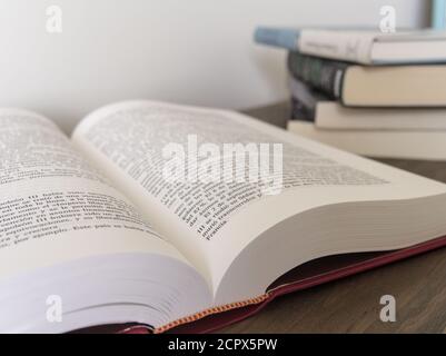 Nahaufnahme eines offenen Buches und eines Bücherstapels Auf dem unscharfen Hintergrund Stockfoto