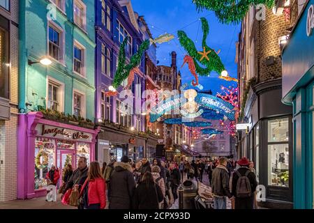 Menschenmassen, die entlang der Carnaby Street London mit den Ocean themed Christmas Lights Overhead, London, UK, laufen Stockfoto