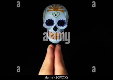 Hände eines Mannes beten zu einem Schädel Kopf von Der Tag der Toten von Hand auf einem gemalt Schwarzer Hintergrund Stockfoto