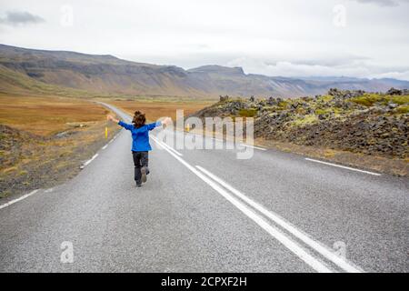 Kind läuft auf einer leeren Straße in der wunderschönen Natur im Snaefellsjokull Nationalpark in Island, Herbstzeit Stockfoto