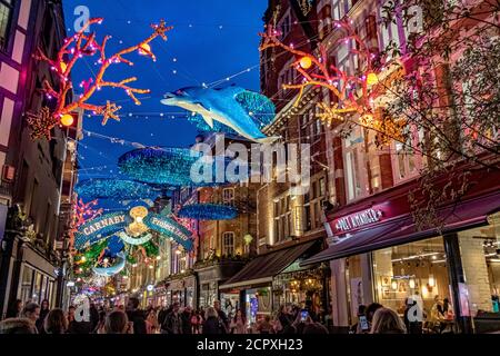 Menschenmassen, die entlang der Carnaby Street London mit den Ocean themed Christmas Lights Overhead, London, UK, laufen Stockfoto