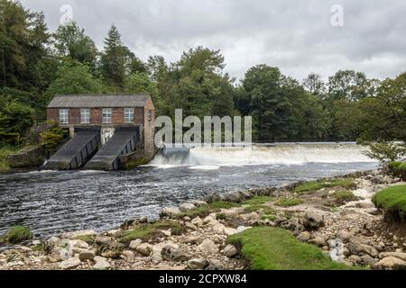 Upper Wehr am River Wharfe bei Grassington mit kleinem Wasserkraftwerk im Yorkshire Dales National Park. Direkt über den Linton Falls. Stockfoto