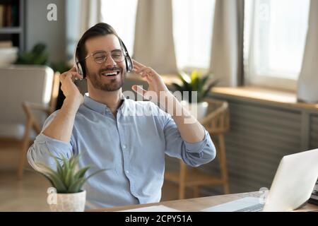 Fröhlicher junger Mann entspannt Musik in Kopfhörern hören Stockfoto
