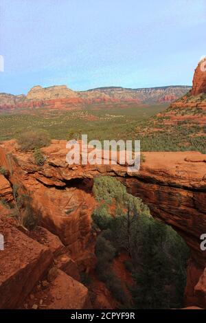 Ein Tal gefüllt mit immergrünen und rotem Sandstein mit weißen Kalksteinbergen im Hintergrund der Devil's Bridge in Sedona, Arizona, USA Stockfoto