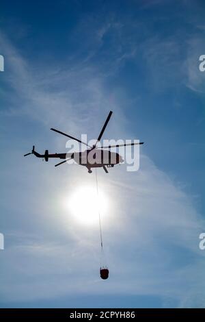 MIL Mi-17 Hubschrauber fliegt in den Himmel mit Eimer Löschwasser Stockfoto