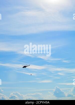 MIL Mi-17 Hubschrauber fliegt in den Himmel mit Eimer Löschwasser Stockfoto