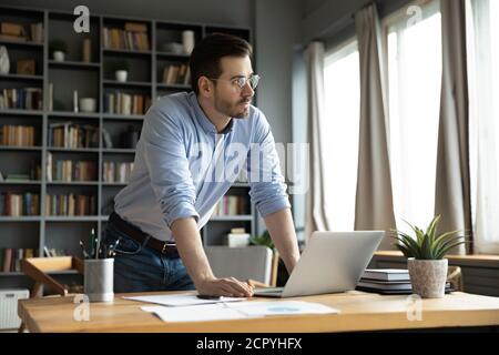 Nachdenklicher kaukasischer Mann lenkte vom Computerdenken ab Stockfoto