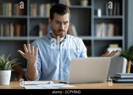 Unglücklicher junger Mann arbeiten auf Laptop verwirrt durch Gadget-Probleme Stockfoto