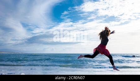 Frau mit langen Haaren läuft am Strand Stockfoto