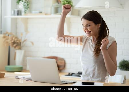 Junge Frau mit Laptop begeistert von Gehaltserhöhung Stockfoto