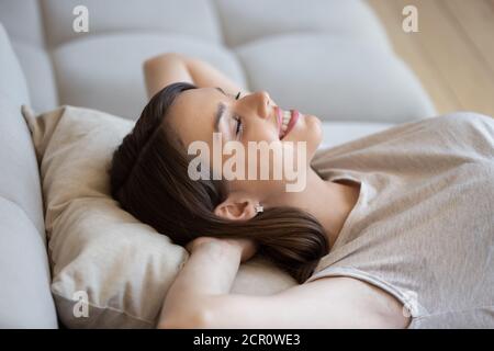 Junge Frau, die zu Hause auf weichem Kissen ruht Stockfoto