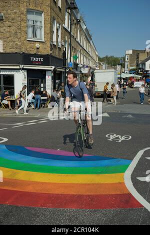 Besucher des Broadway Market radeln auf verkehrsfreien Straßen mit Straße Schilder, die darauf hinweisen, dass die soziale Distanz wegen Coronavirus sicher gehalten werden sollte Covid-19 Stockfoto