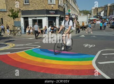 Besucher des Broadway Market radeln auf verkehrsfreien Straßen mit Straße Schilder, die darauf hinweisen, dass die soziale Distanz wegen Coronavirus sicher gehalten werden sollte Covid-19 Stockfoto