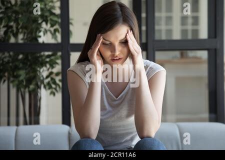 Müde, gut aussehende junge Frau, die unter Kopfschmerzen und anrührenden Schläfen leidet Stockfoto