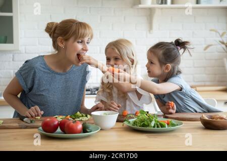 Fürsorgliche Töchter füttern Mama mit Gemüse Stockfoto