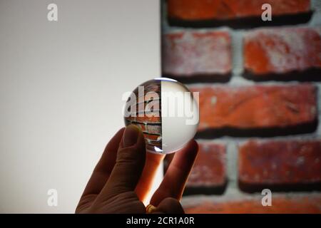 Glaskugel mit umgekehrter Reflexion in der Hand Stockfoto