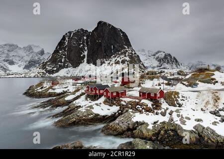 Landschaft der Lofoten-Inseln in Norwegen mit traditionellem Holz Rote Fischerhütten vor dem Meer und dies Schöne Moutain im Hintergrund Stockfoto